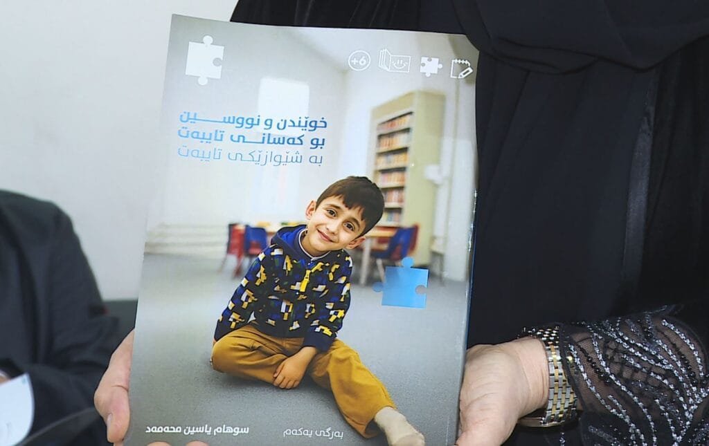 Dayîkekê ji bo zarokê xwe yê bi otîstîk pirtûk...